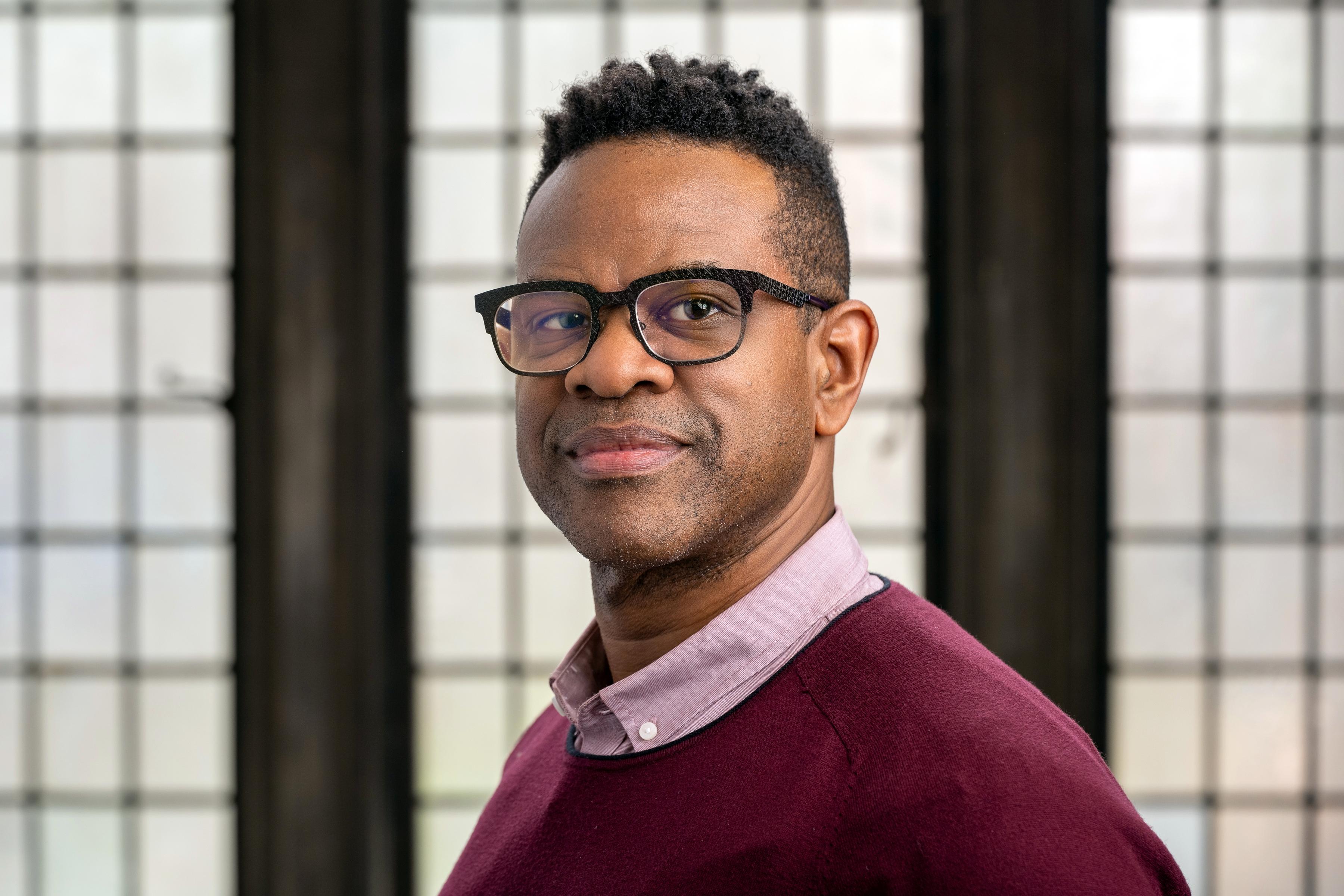 Brown-skinned Black man with glasses and short curly hair.