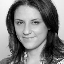 Mai Iskander looks directly at the camera while smiling. The photo is in black and white.