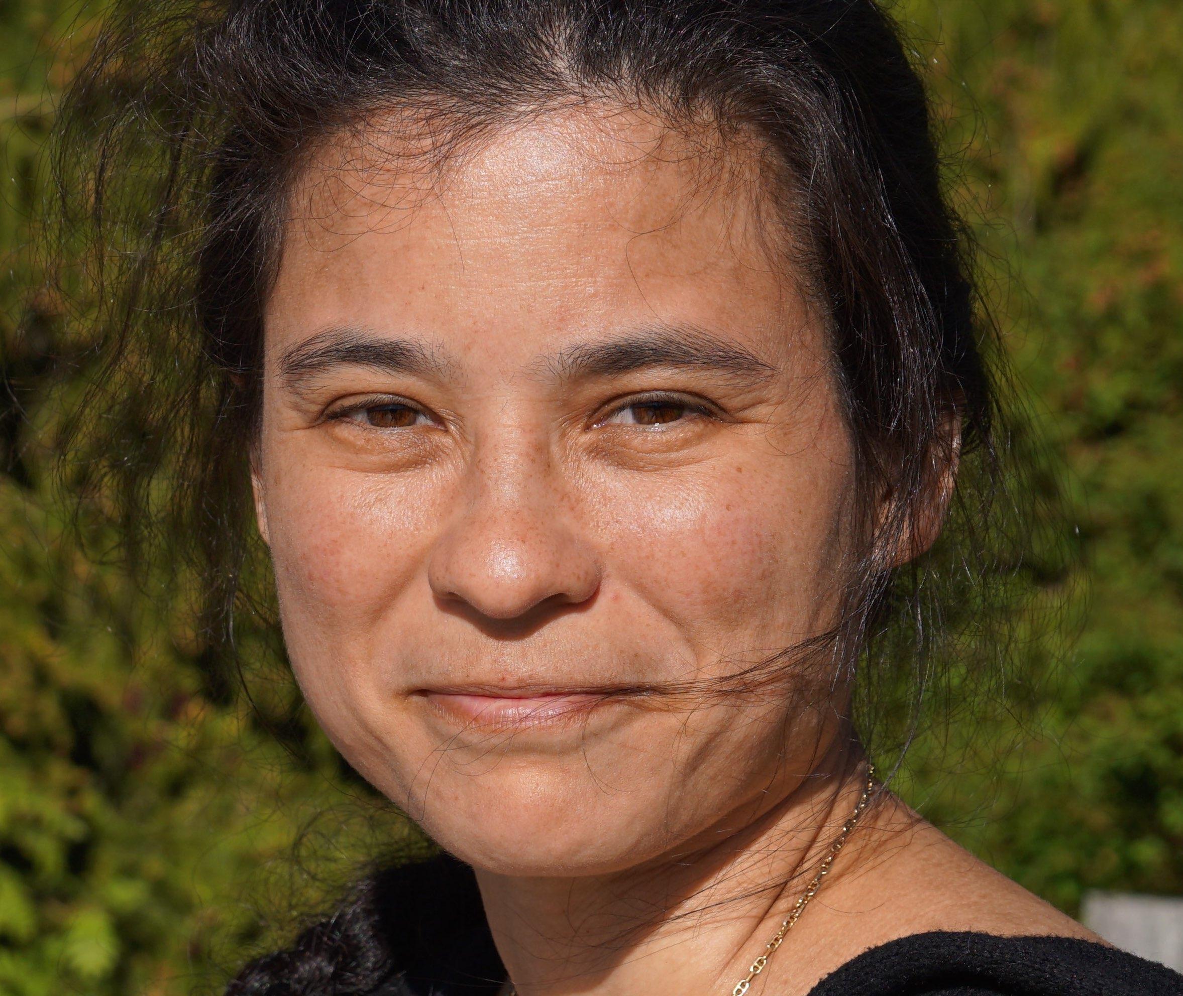 A photo of a woman in the sunlight smiling at the camera.