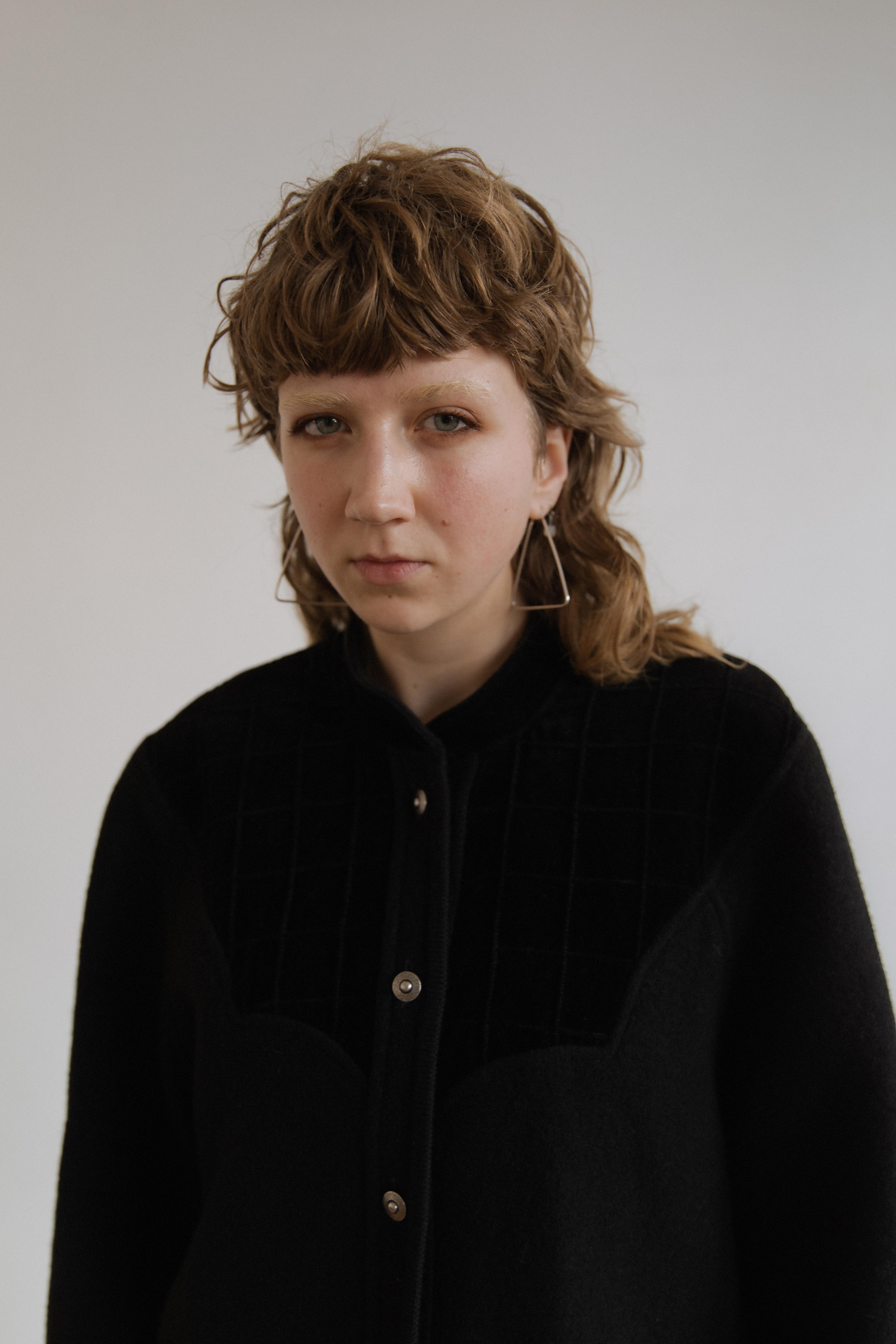 A portrait of Fiona Guy Hall against a grey background.