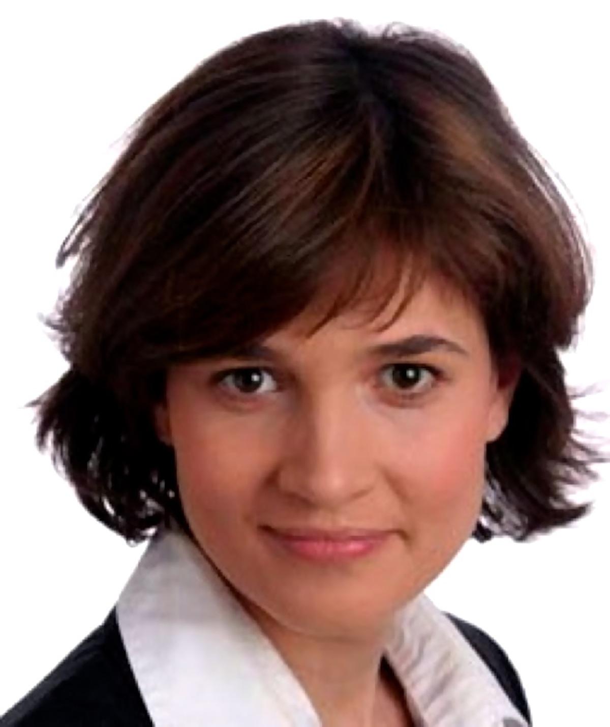 A portrait of a woman wearing a button down and blazer looking into the camera.