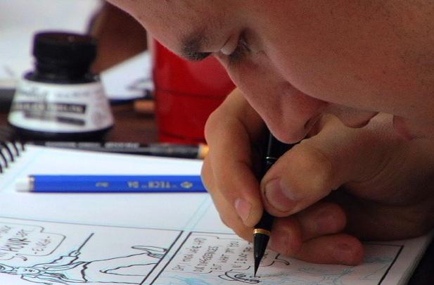 A student draws a cartoon intently.