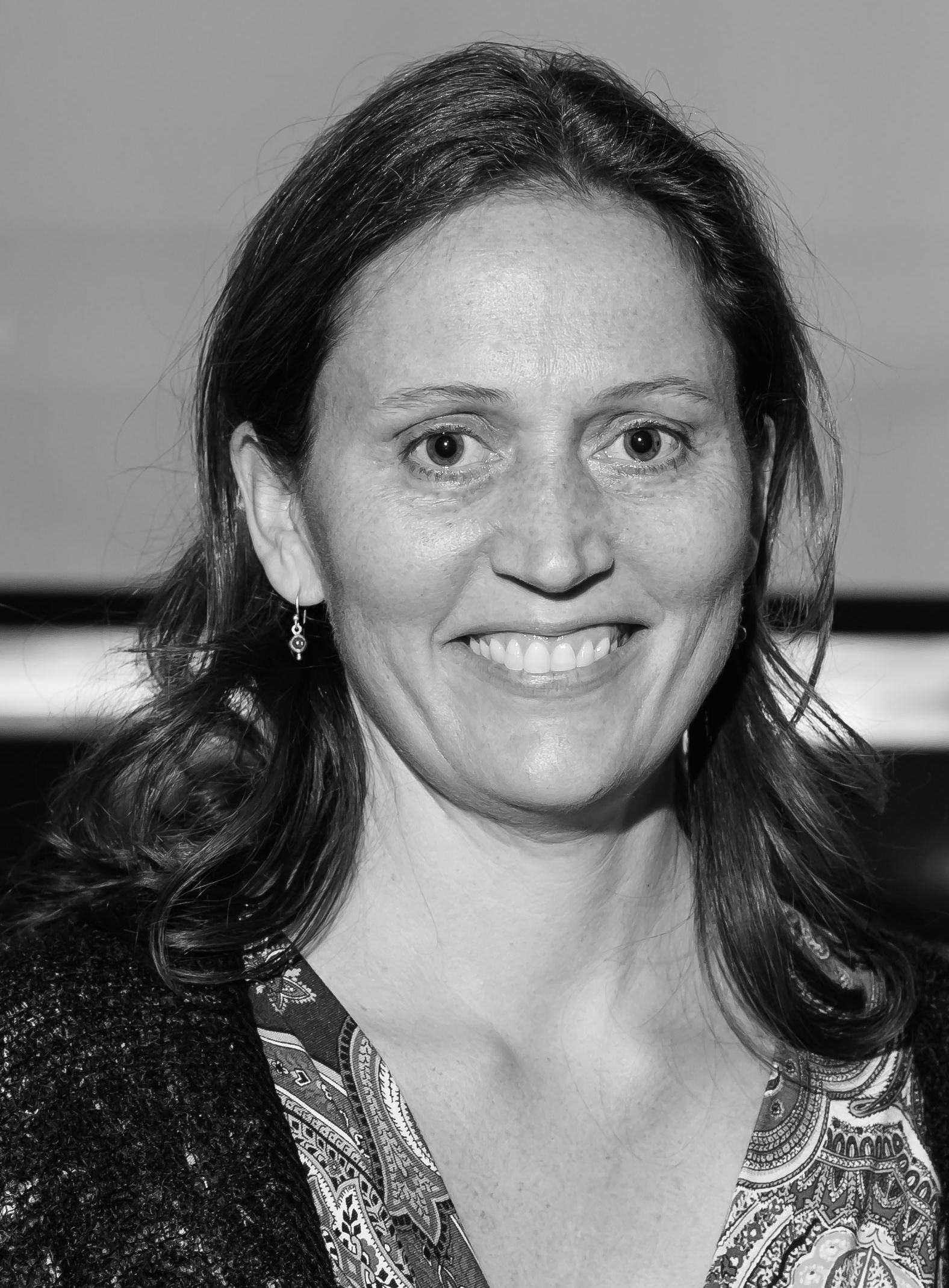 A black and white photo of a woman at an event smiling at the camera.
