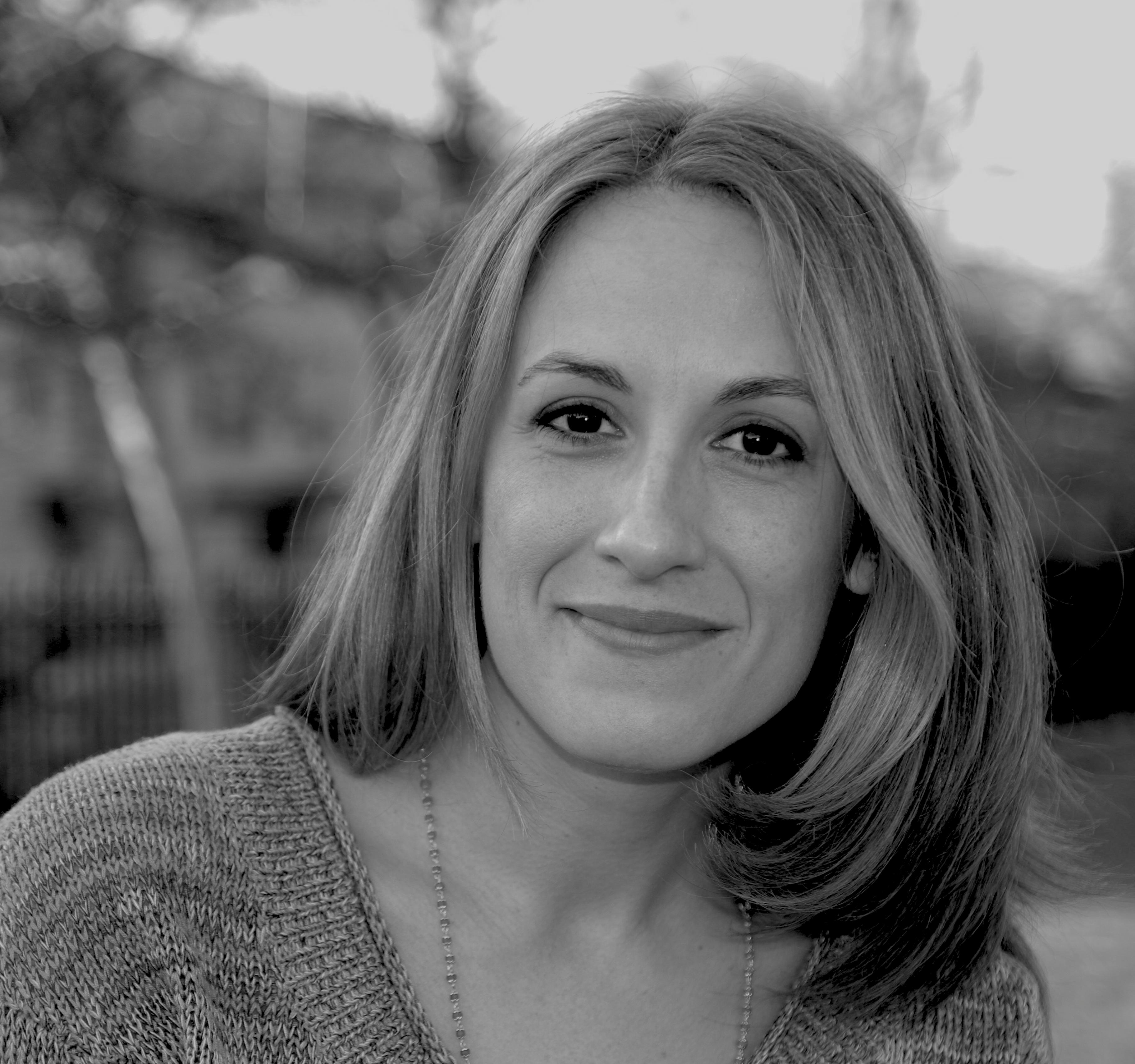 A black and white portrait of a woman smiling into the camera.