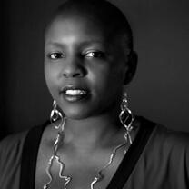 A woman wearing earrings and a necklace smiles at the camera