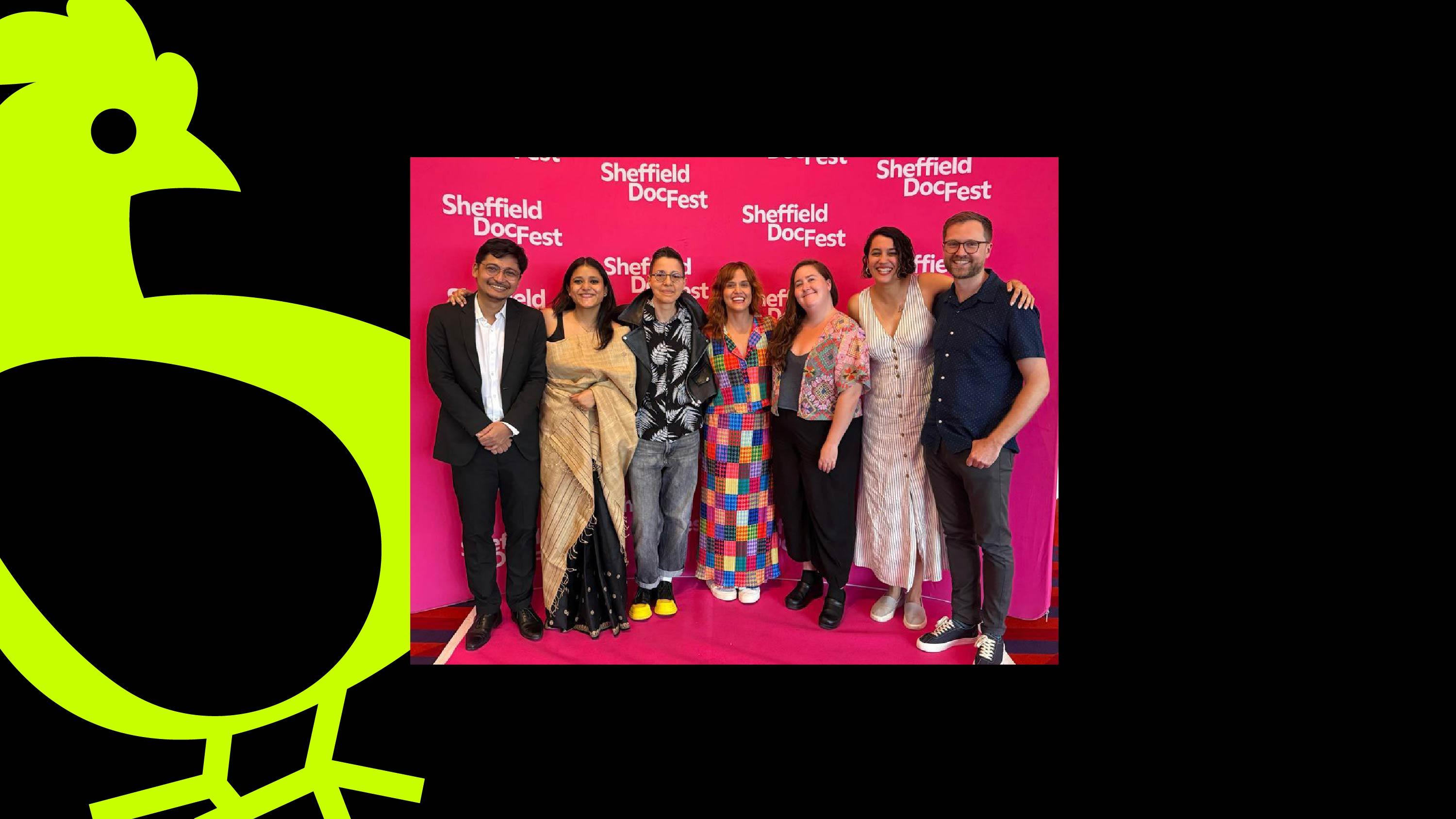 A photo of a group of people smiling in front of a hot pink step and repeat that reads "Sheffield DocFest." Next to the photo, text reads "Chicken & Egg Films WIP Showcase" and "Sheffield DocFest."