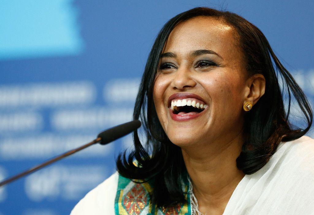 Black woman with shoulder length black air at microphone smiling