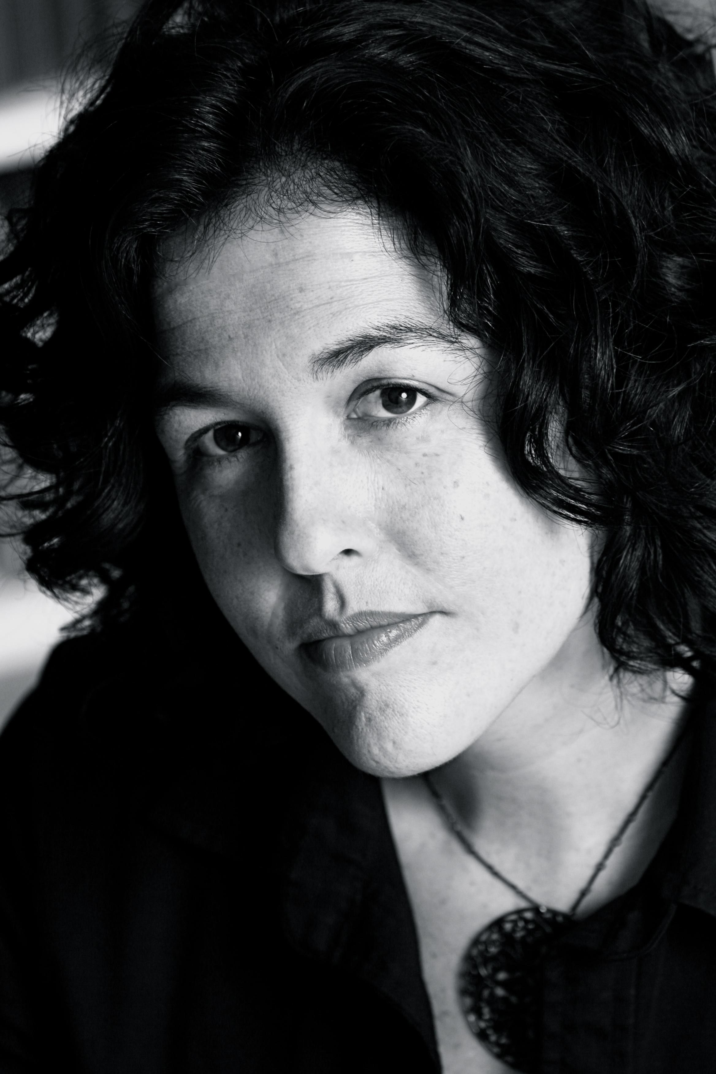 A black and white photo of a woman looking into the camera with a serious expression.