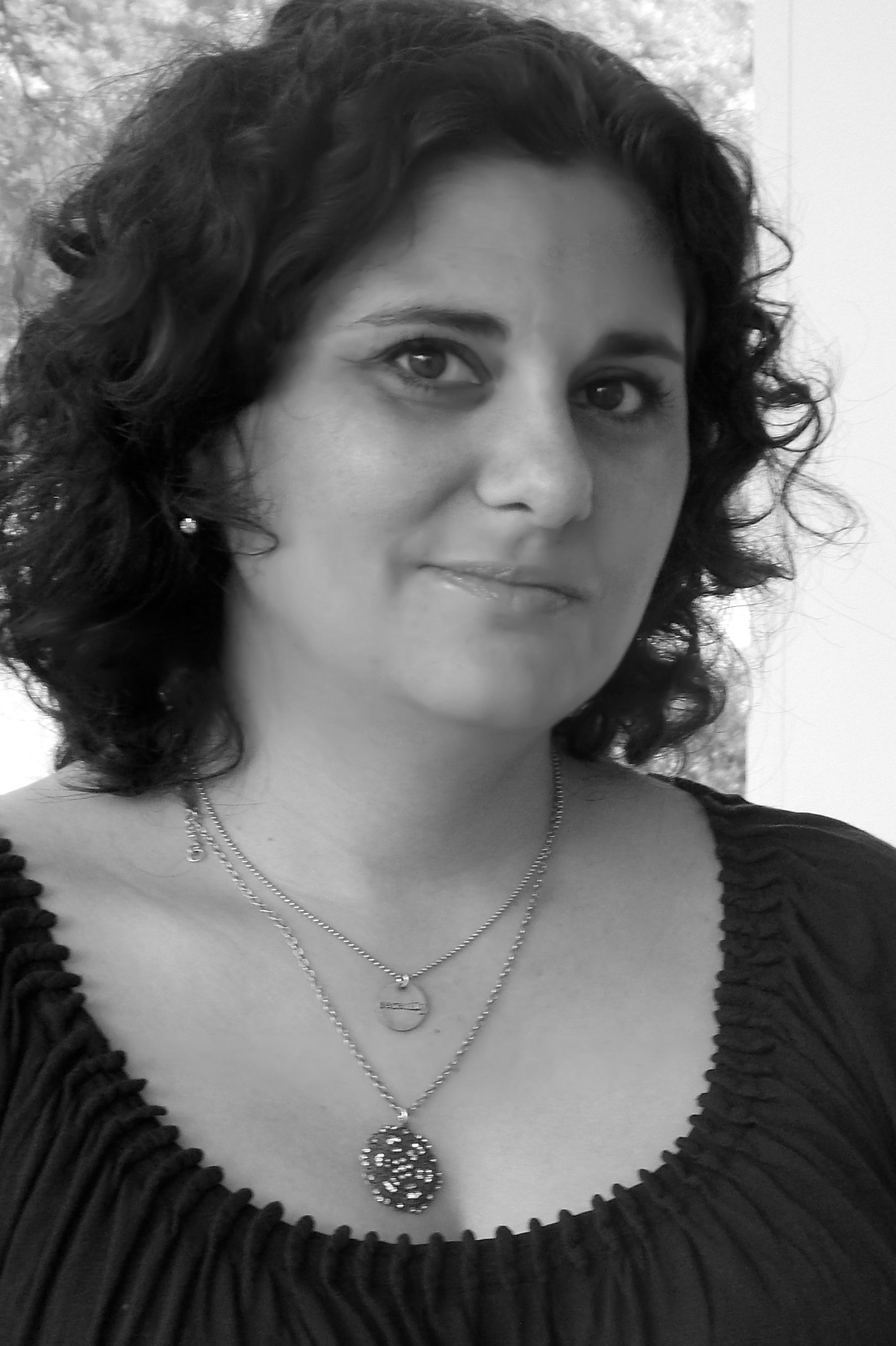 A black and white photo of a woman smiling at the camera.