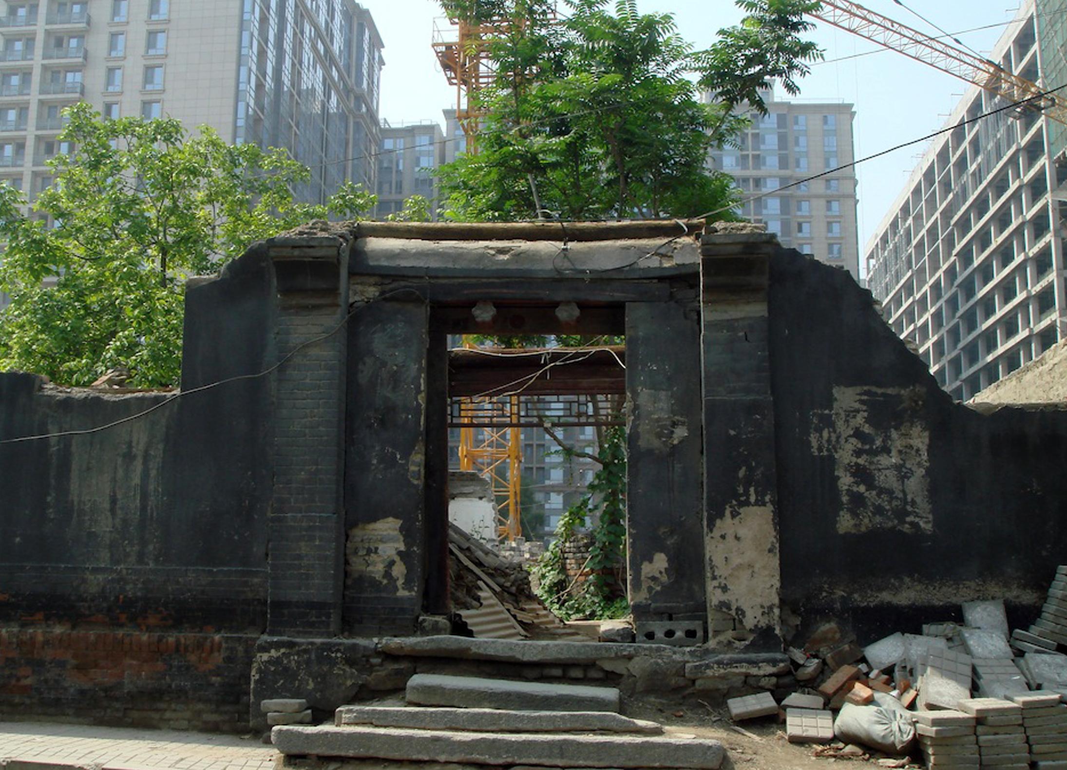 An old archway surrounded by skyscrapers and construction.