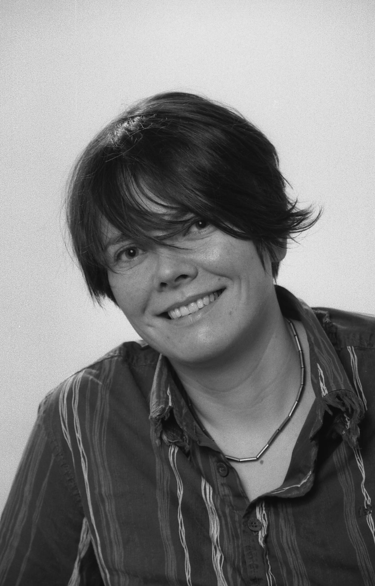 Eva Weber Smiles at Camera. Eva has short brown hair and this photo was taken in Black and White.