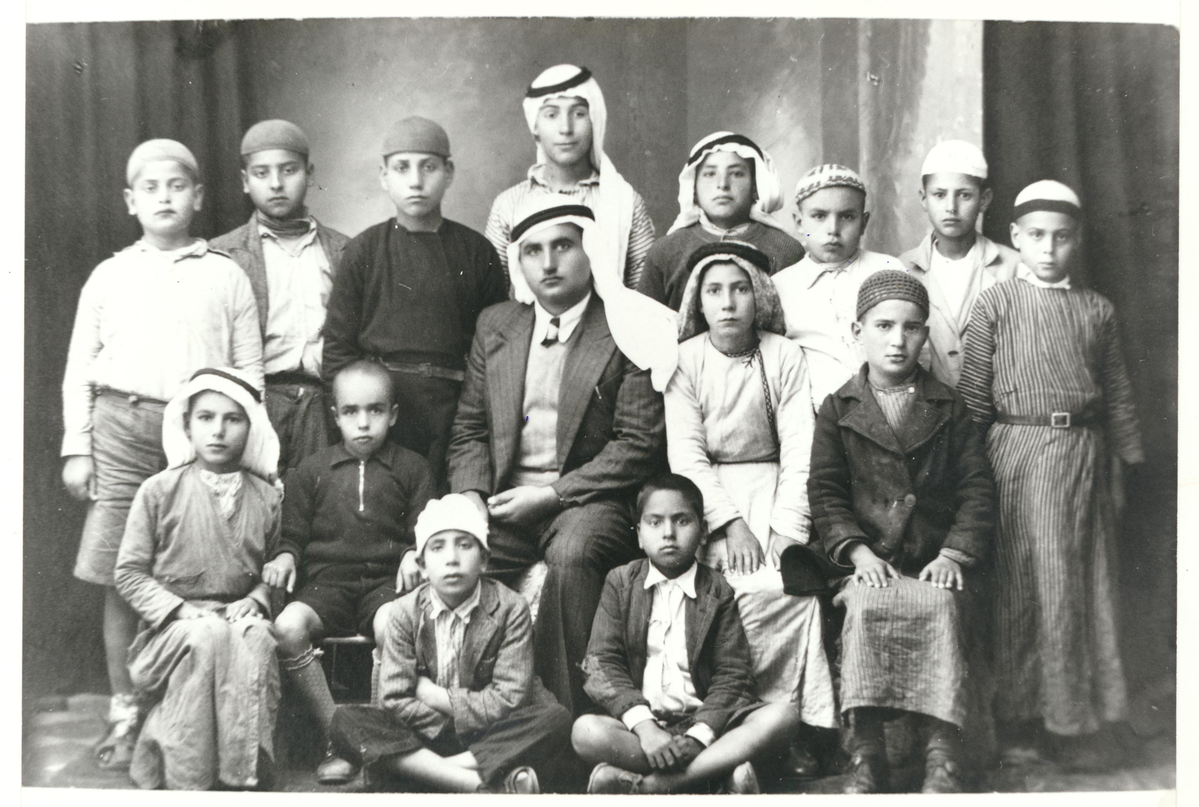 A group of children lined up for a professional photo. The black-and-white photo is grainy, implying that it is from decades ago.
