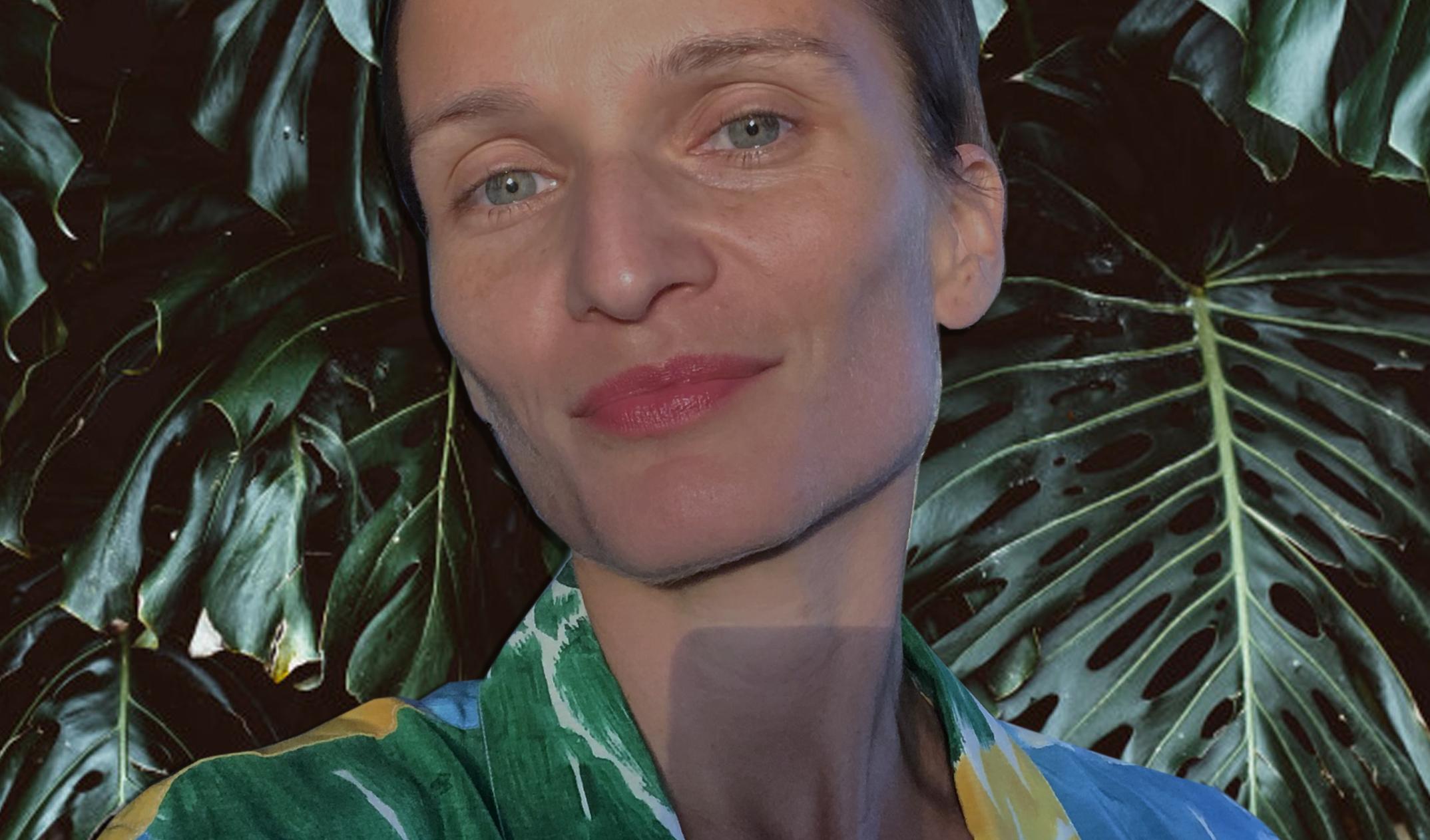 Iva Radivojević looks directly at the camera. She is standing by a background of dark green foliage.