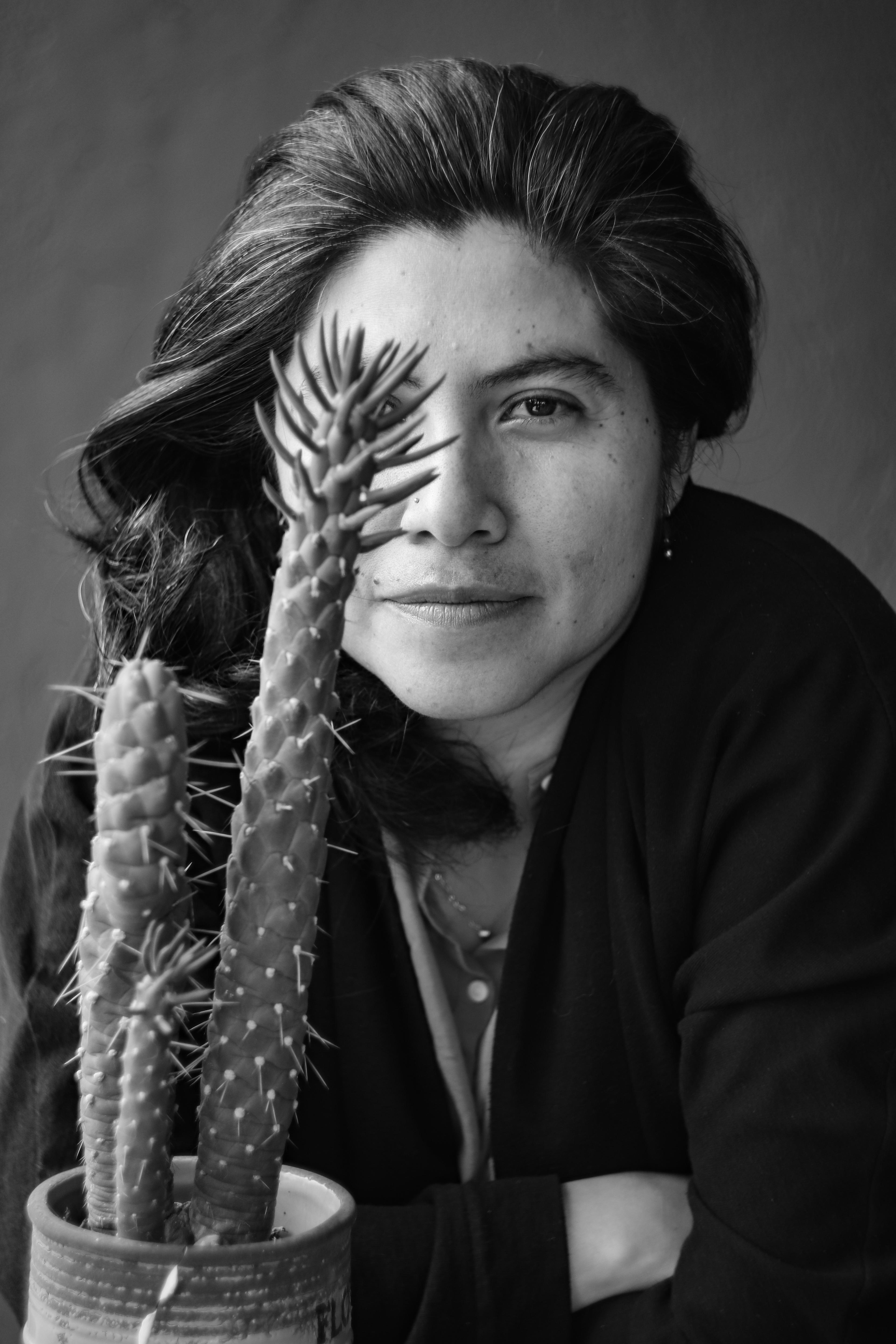 An unconventional headshot of Sandra Luz Lopez Barroso in black in white. Half of her face is not visible, having to do with her actual search: she can’t see it all yet.