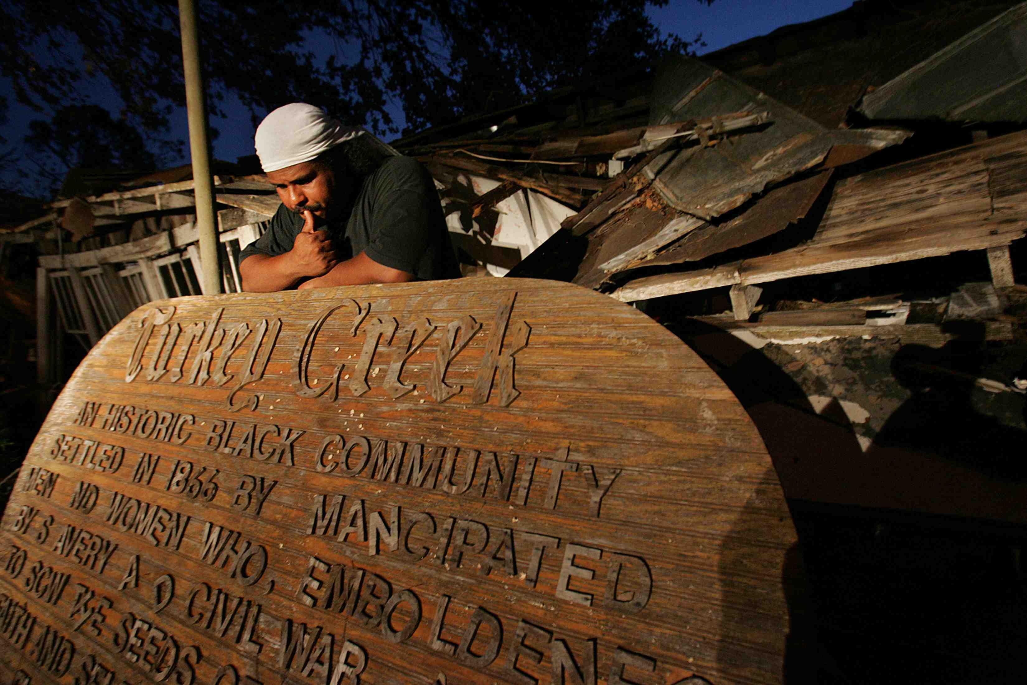 photo of a man leaning over a sign titled "Turkey Creek".