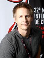 Daniel Junge looks at the camera smiling. He has short hair and is wearing a grey shirt.