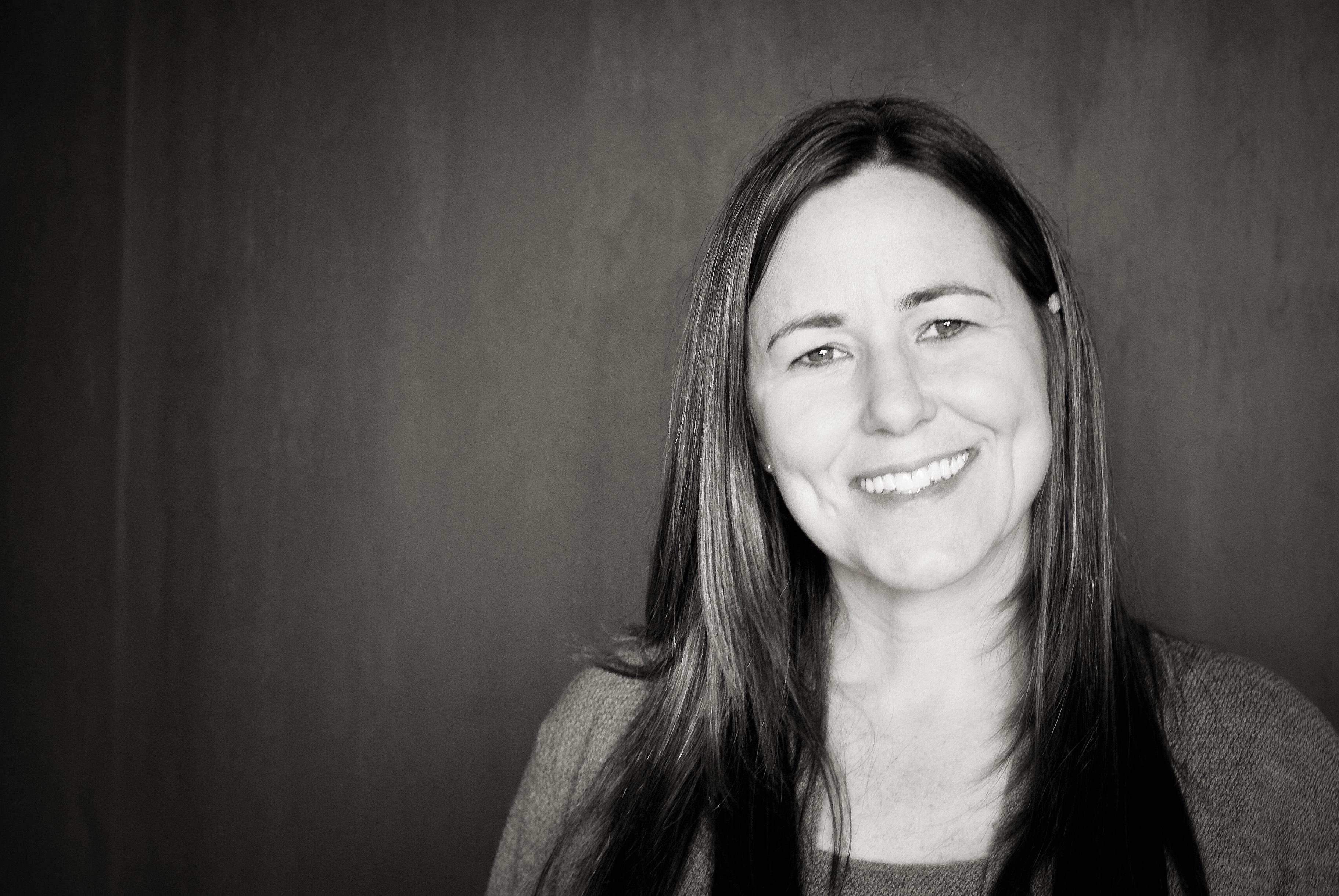 A black and white portrait of a woman smiling at the camera.
